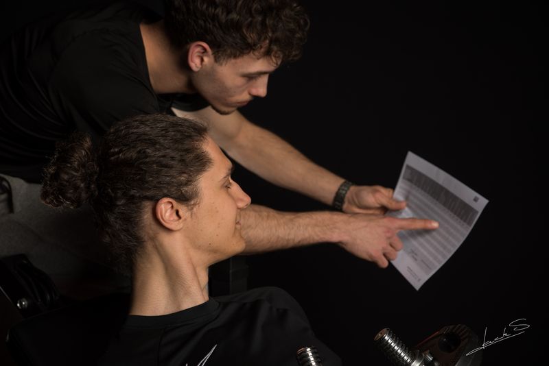 Trainingsschema op maat op papier: de coach wijst de oefeningen, series en gewichten aan bij een klant