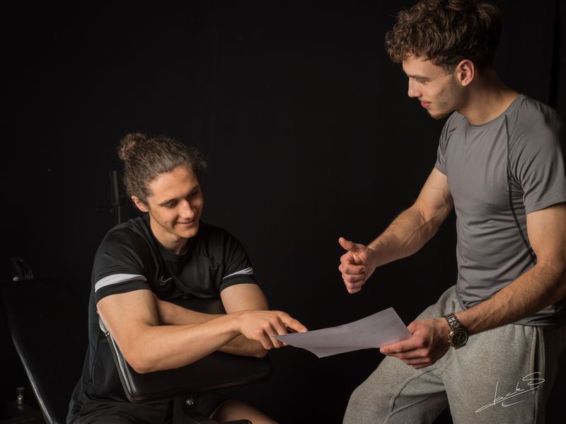 Coach en klant overlopen samen een trainingsschema op maat: series, herhalingen en gewichten per oefening